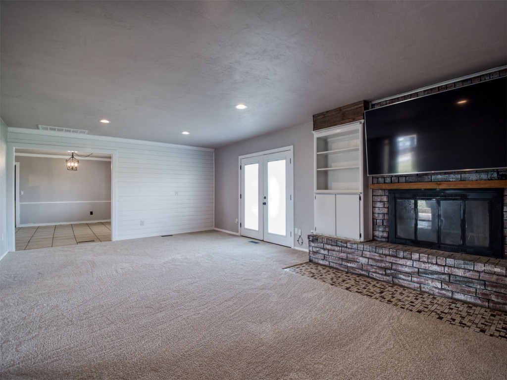 805 S Hwy 76 Highway, Newcastle, OK 73065 unfurnished living room featuring light carpet, french doors, and a brick fireplace