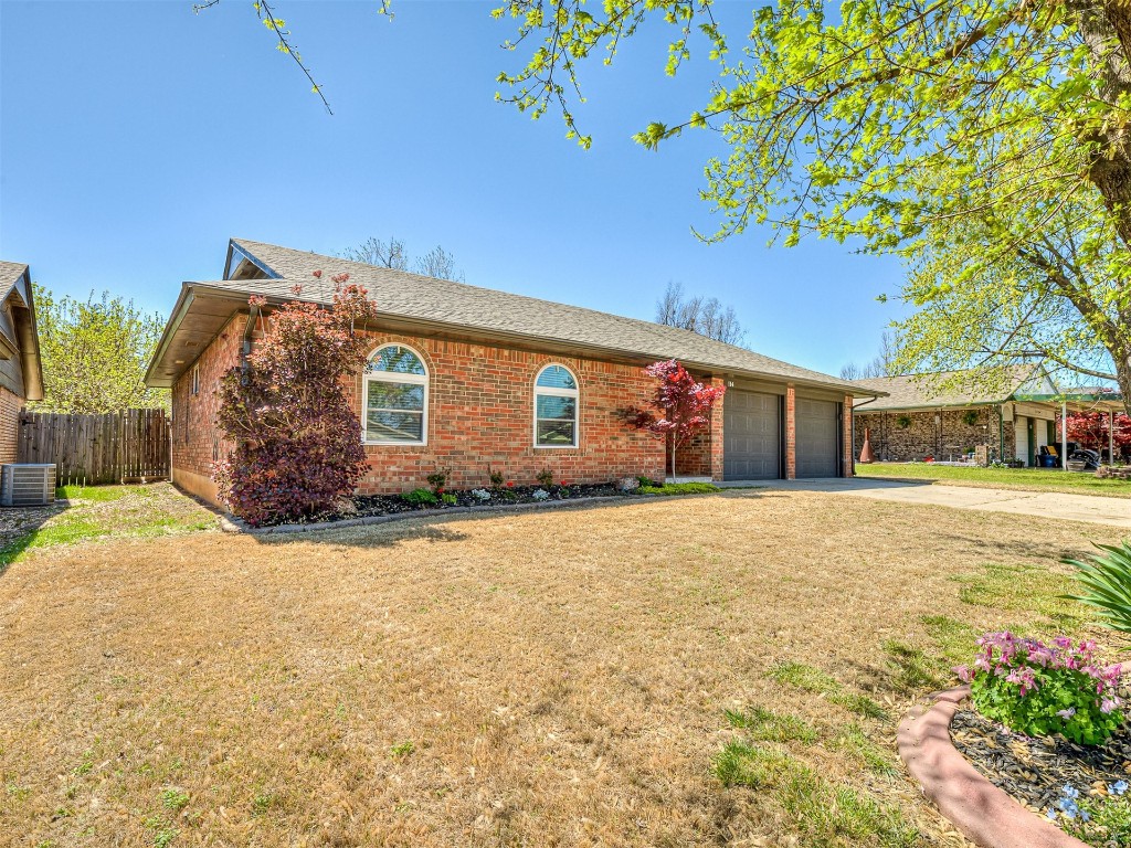 114 E Cypress Avenue, Yukon, OK 73099 ranch-style house featuring a front lawn, a garage, and central air condition unit