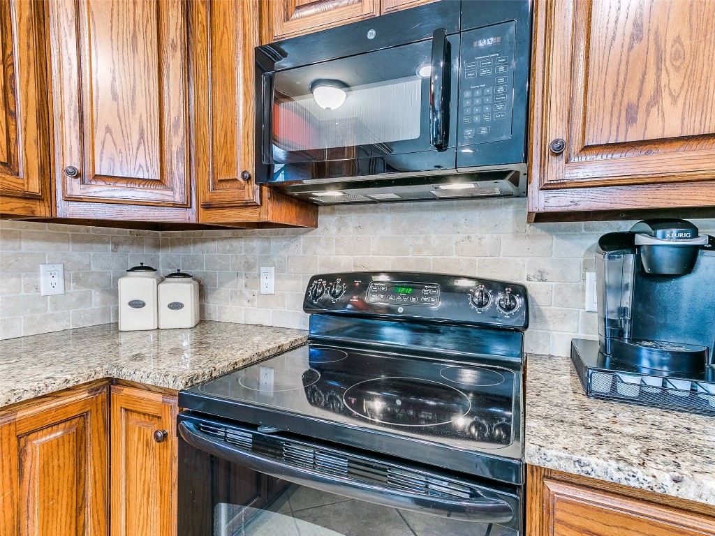1738 W Rose Oak Drive, Mustang, OK 73064 kitchen featuring light stone countertops, backsplash, and black appliances