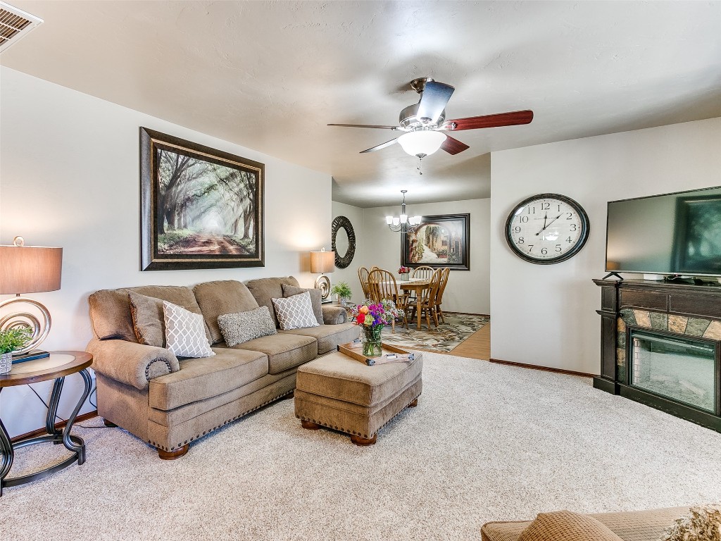 1738 W Rose Oak Drive, Mustang, OK 73064 living room featuring light carpet and ceiling fan with notable chandelier