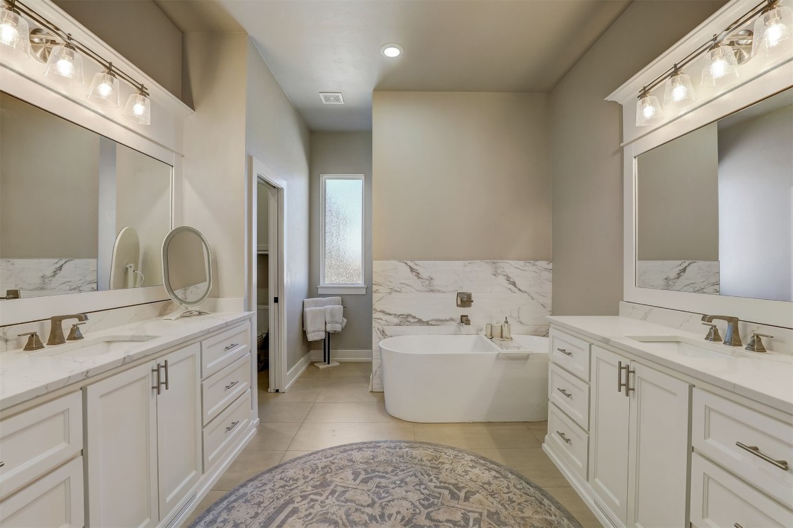 2273 NW 223rd Street, Edmond, OK 73025 bathroom with a bathing tub, tile floors, tile walls, and dual bowl vanity