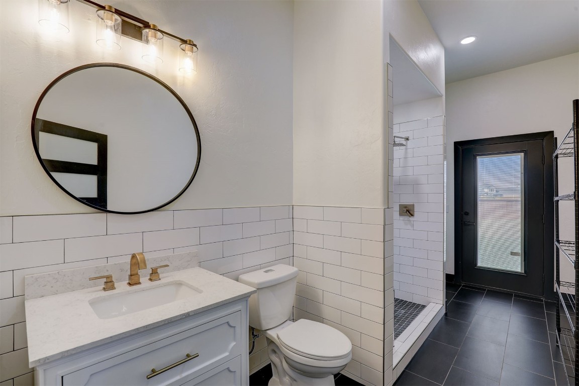 2273 NW 223rd Street, Edmond, OK 73025 bathroom with toilet, vanity, tile walls, tile flooring, and a tile shower