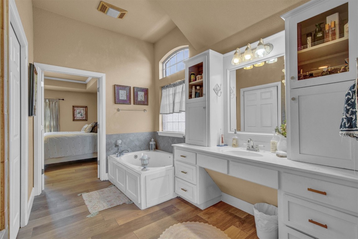 1312 SW 126th Street, Oklahoma City, OK 73170 bathroom featuring lofted ceiling, wood-type flooring, vanity, and a tub