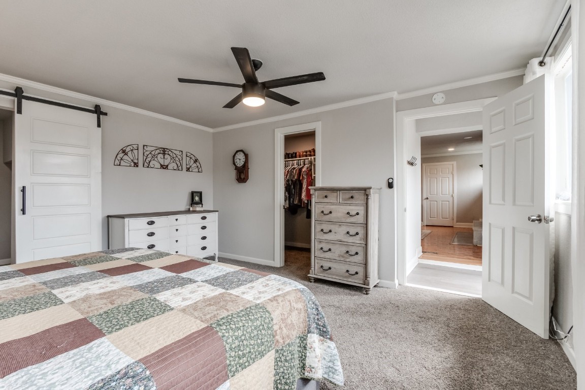 2736 Pembroke Terrace, Oklahoma City, OK 73116 bedroom featuring ceiling fan, a closet, a barn door, light carpet, and a spacious closet