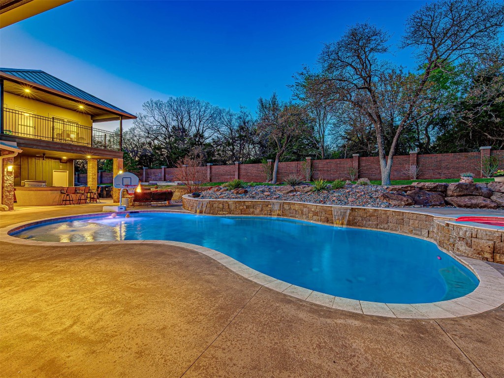 4101 Oakdale Farm Circle, Edmond, OK 73013 pool at dusk with pool water feature, a hot tub, and a patio