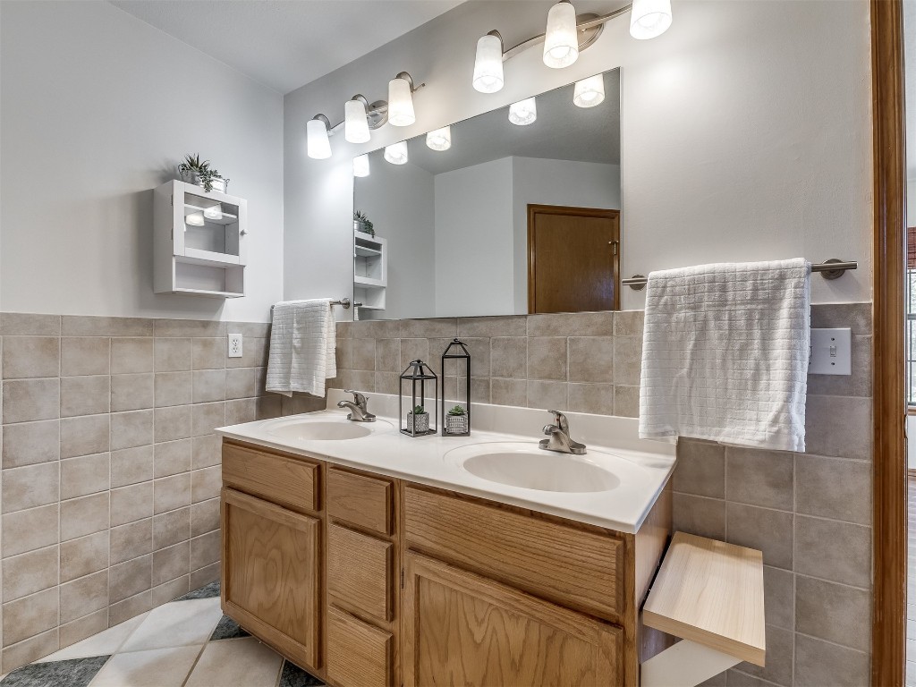 100 Parkdale Court, Noble, OK 73068 bathroom featuring vanity with extensive cabinet space, tasteful backsplash, tile walls, dual sinks, and tile floors
