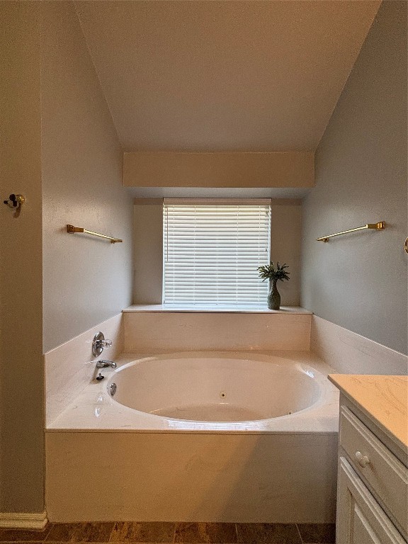 8304 NW 75th Street, Oklahoma City, OK 73132 bathroom featuring vaulted ceiling, tile flooring, vanity, and a tub