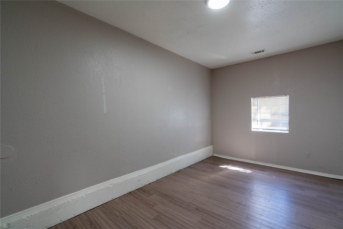 301 NW 80th Street, Oklahoma City, OK 73114 spare room featuring a textured ceiling and hardwood / wood-style floors