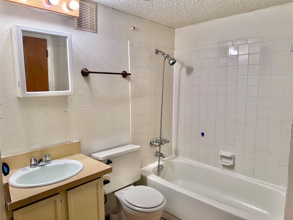1100 SW 101st Street, Oklahoma City, OK 73139 full bathroom with vanity, a textured ceiling, toilet, and tiled shower / bath