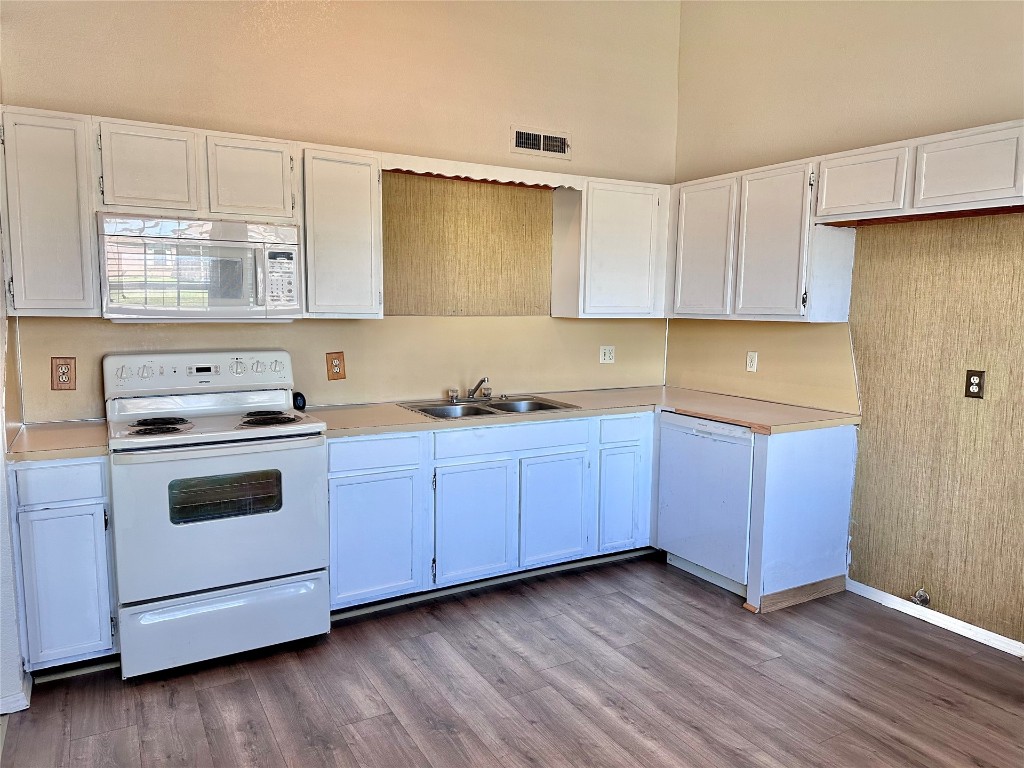 1100 SW 101st Street, Oklahoma City, OK 73139 kitchen with dark hardwood / wood-style flooring, white appliances, and white cabinetry