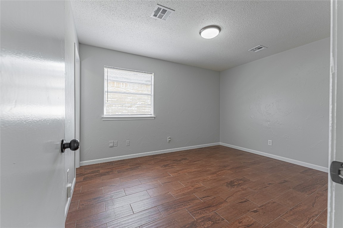 11012 N Mckinley Avenue, Oklahoma City, OK 73114 spare room featuring dark hardwood / wood-style floors and a textured ceiling