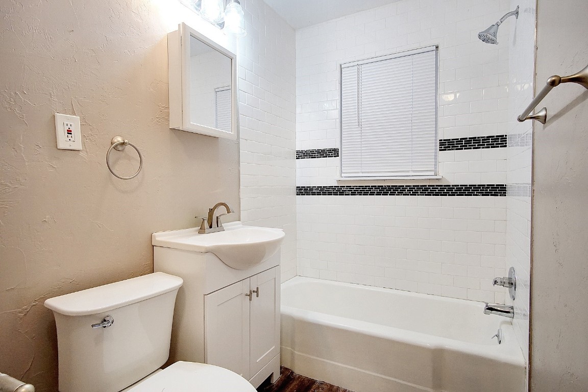 6220 SE 7th Street, Midwest City, OK 73110 full bathroom featuring tiled shower / bath combo, vanity, toilet, and hardwood / wood-style flooring