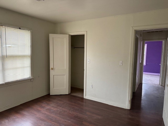 1713 N Quapah Avenue, Oklahoma City, OK 73107 unfurnished bedroom with a closet, dark hardwood / wood-style floors, and multiple windows