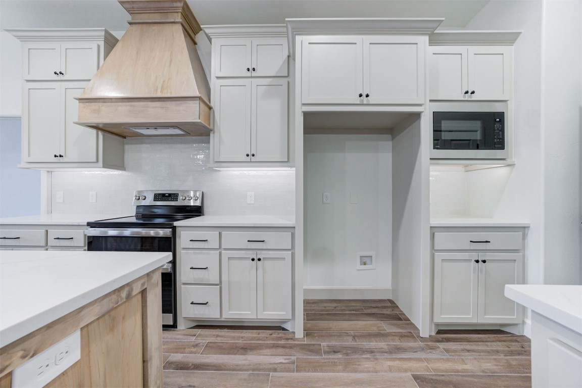 2004 Leo Court, Blanchard, OK 73010 kitchen with white cabinets, premium range hood, black microwave, and electric range