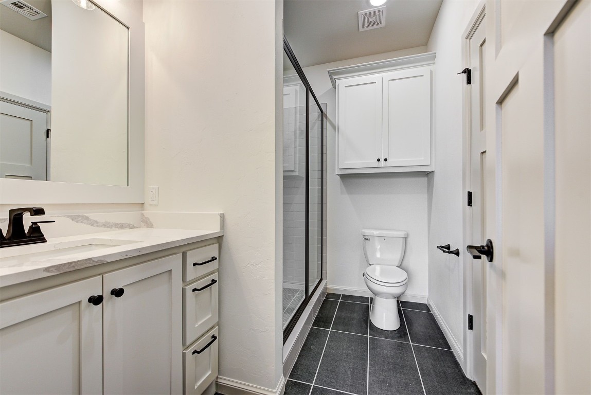 5716 Goldstone Court, Mustang, OK 73064 bathroom featuring a shower with door, tile floors, toilet, and vanity
