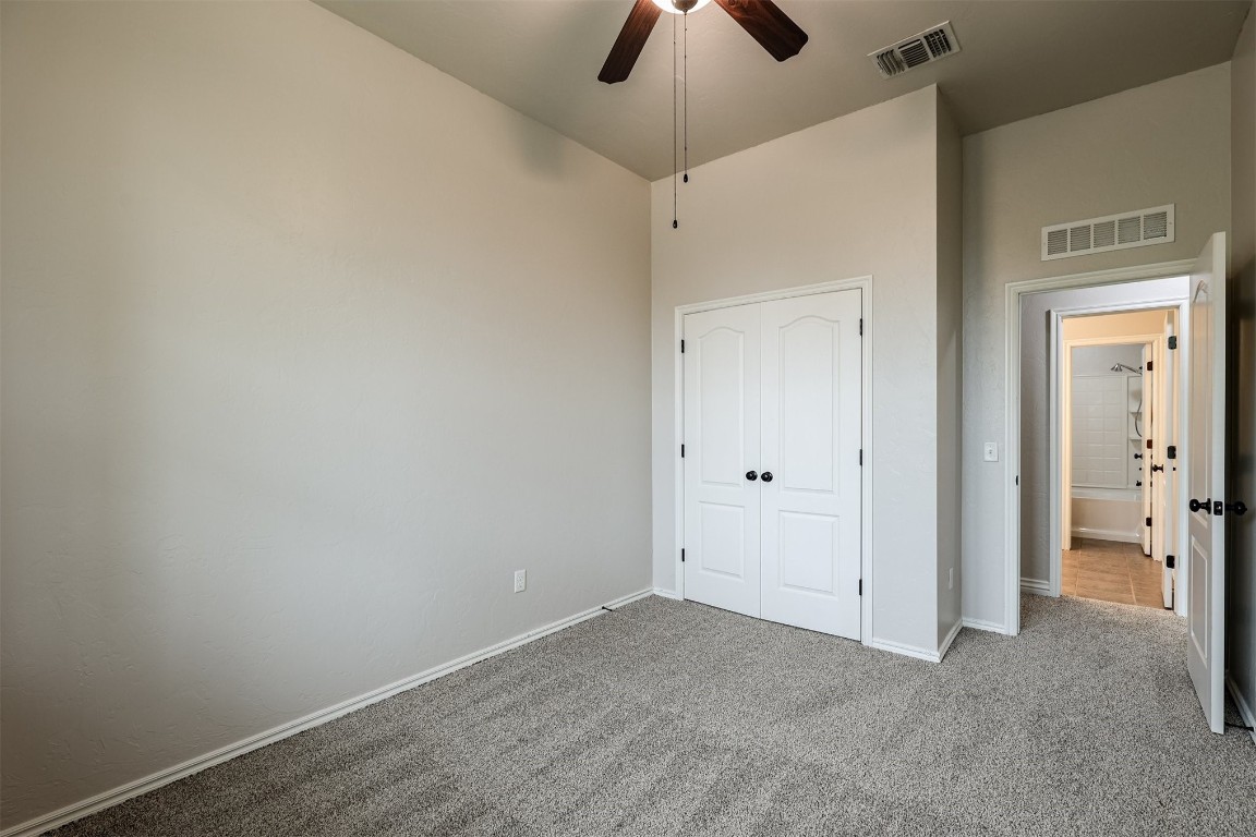 317 Partridge Run Road, Yukon, OK 73099 unfurnished bedroom with a towering ceiling, ceiling fan, light colored carpet, and a closet