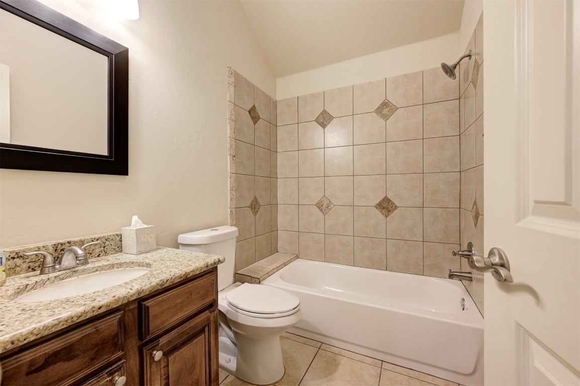 11748 SW 21st Street, Yukon, OK 73099 full bathroom featuring toilet, vanity, tiled shower / bath, lofted ceiling, and tile floors