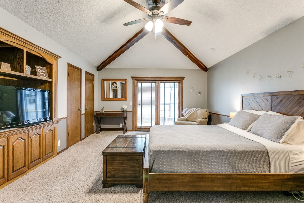 6201 Inland Road, Warr Acres, OK 73132 bedroom featuring ceiling fan, lofted ceiling with beams, a textured ceiling, and light colored carpet