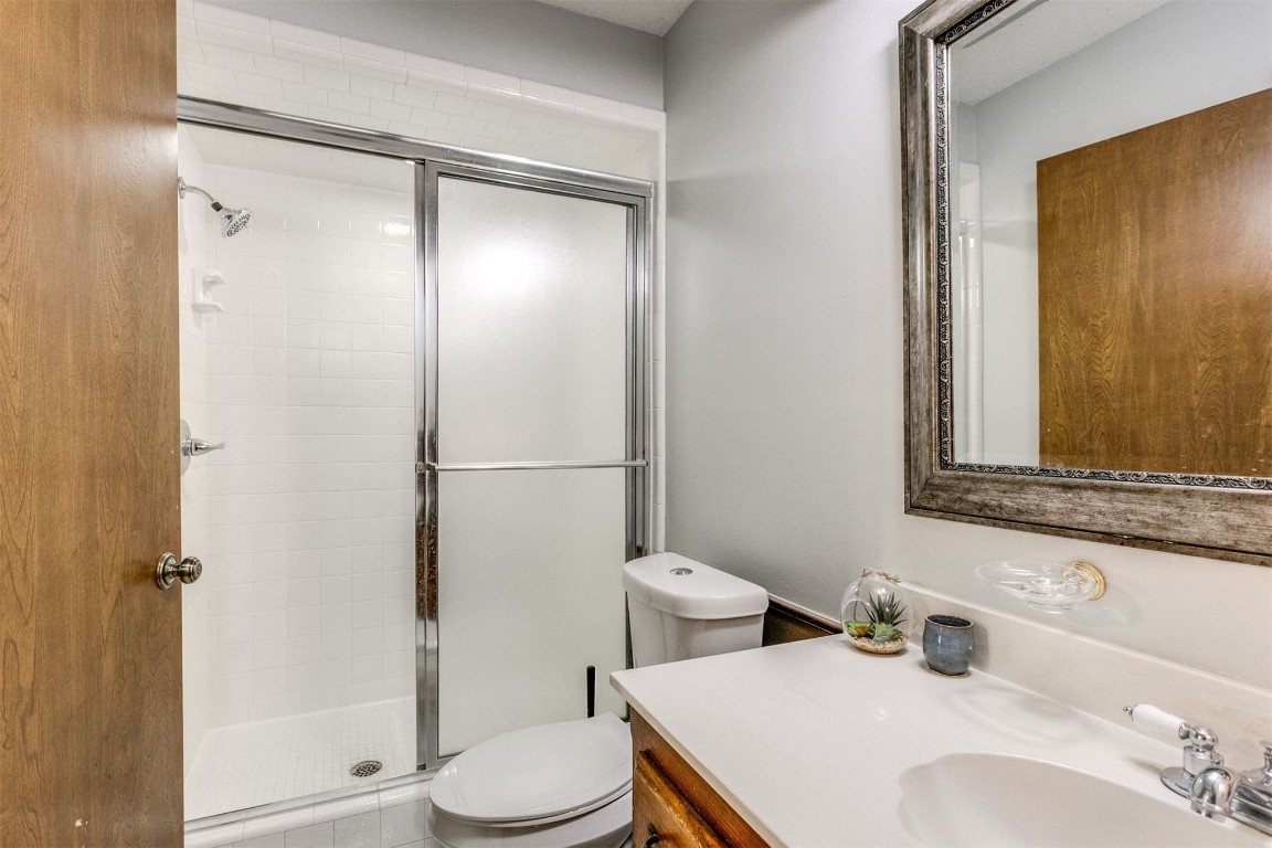 6201 Inland Road, Warr Acres, OK 73132 bathroom featuring large vanity, toilet, and a shower with shower door
