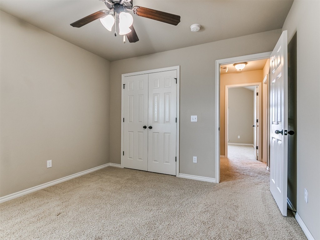 10012 Squire Lane, Yukon, OK 73099 unfurnished bedroom featuring light carpet, a closet, and ceiling fan