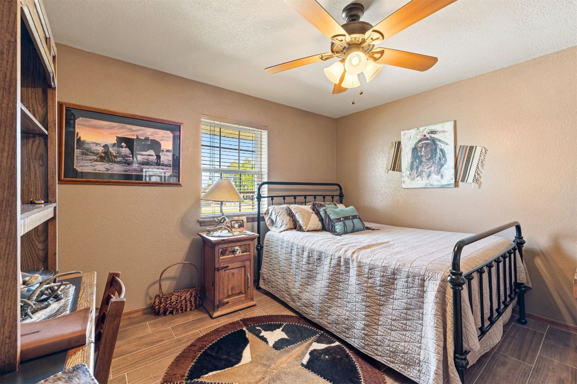1524 W Oak Street, El Reno, OK 73036 bedroom with dark hardwood / wood-style floors, ceiling fan, and a textured ceiling