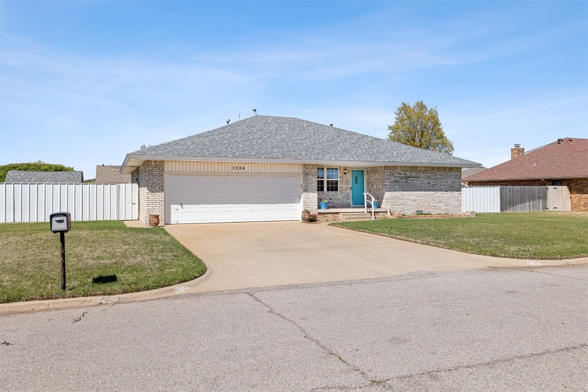 1524 W Oak Street, El Reno, OK 73036 ranch-style house with a garage and a front lawn