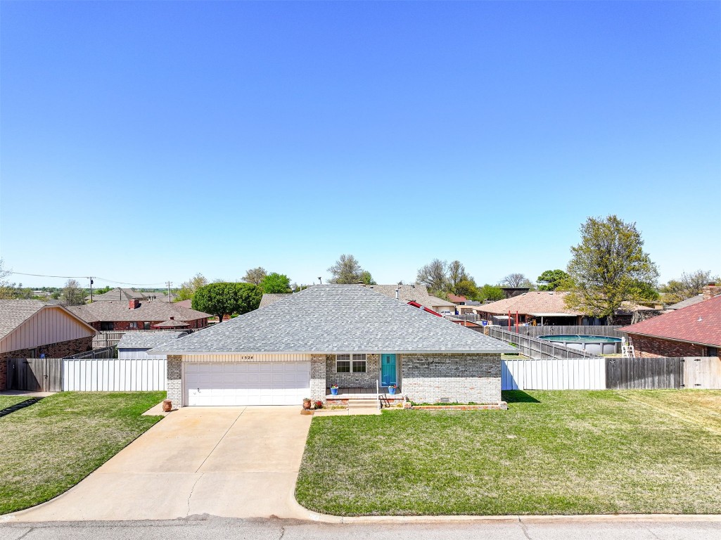 1524 W Oak Street, El Reno, OK 73036 ranch-style home featuring a garage and a front yard