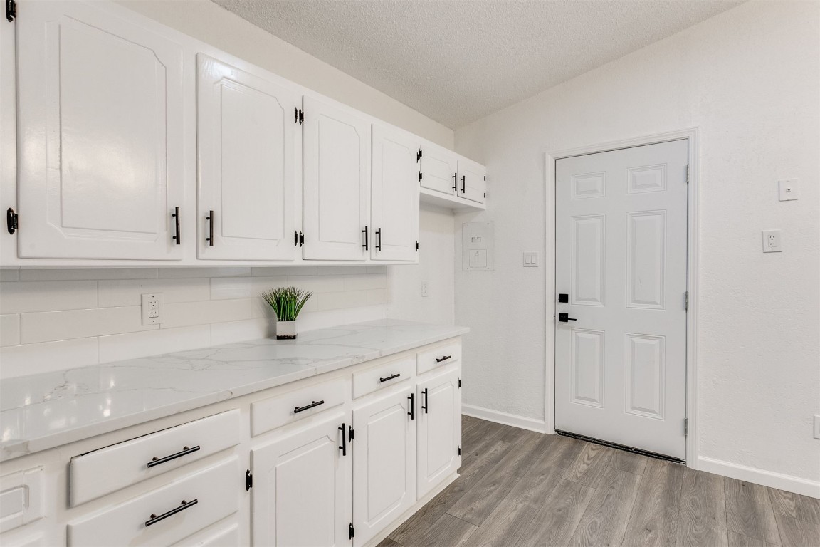 529 NW 92nd Street, Oklahoma City, OK 73114 kitchen with white cabinets, light hardwood / wood-style flooring, backsplash, and light stone counters