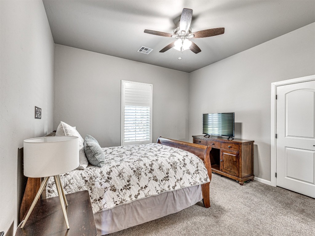 1965 Ladera Lane, Edmond, OK 73034 bedroom with light colored carpet and ceiling fan