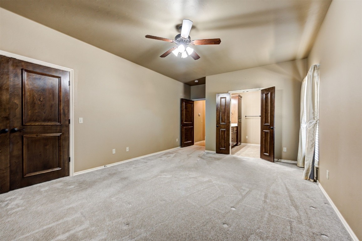 12600 N Rockwell Avenue, #78, Oklahoma City, OK 73142 unfurnished bedroom with light colored carpet, ceiling fan, and ensuite bathroom