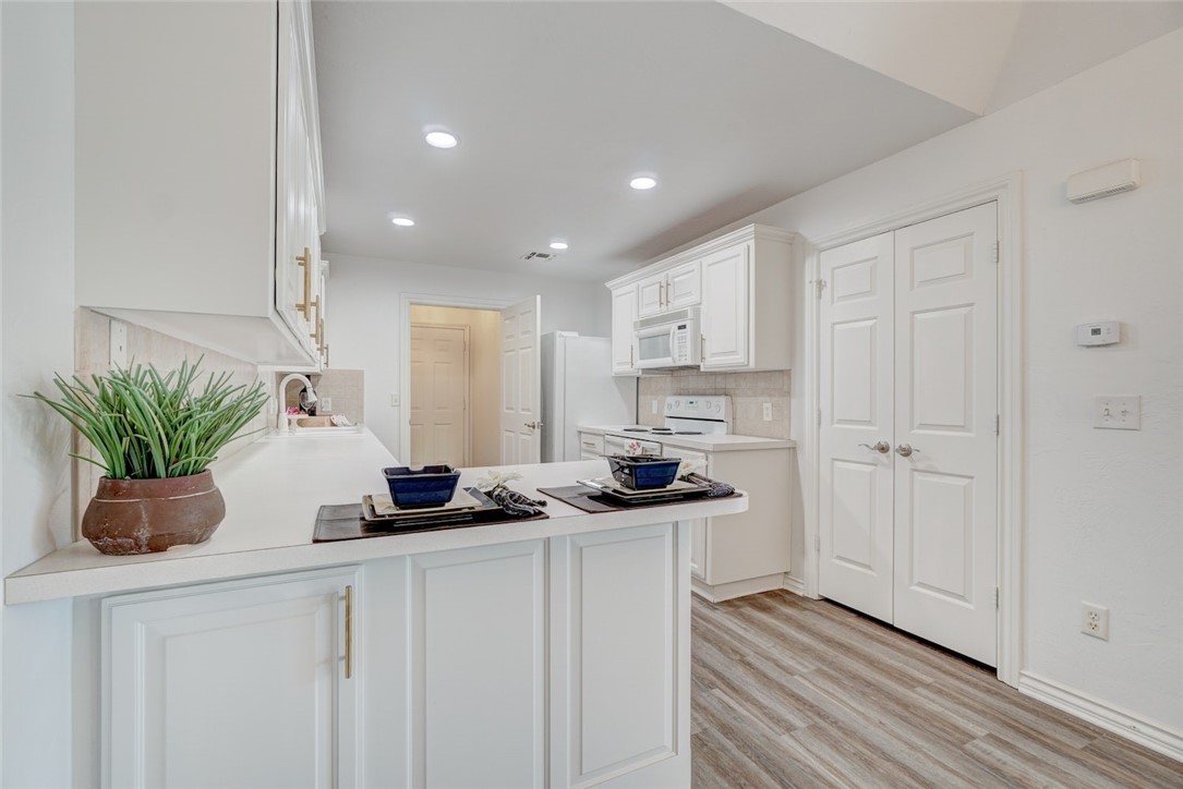 300 Glen Drive, Yukon, OK 73099 kitchen with backsplash, white appliances, white cabinets, sink, and light wood-type flooring