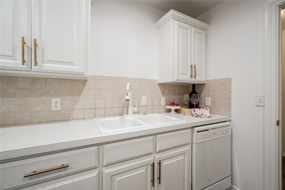 300 Glen Drive, Yukon, OK 73099 kitchen with white cabinetry, tasteful backsplash, white dishwasher, and sink