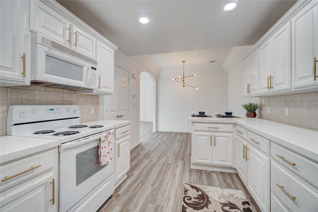 300 Glen Drive, Yukon, OK 73099 kitchen with light hardwood / wood-style flooring, white appliances, tasteful backsplash, and white cabinetry
