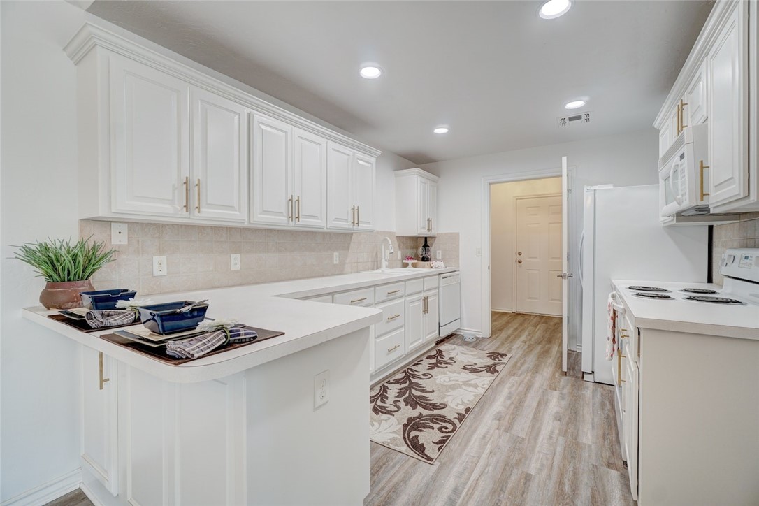300 Glen Drive, Yukon, OK 73099 kitchen featuring white cabinets, white appliances, backsplash, and light wood-type flooring