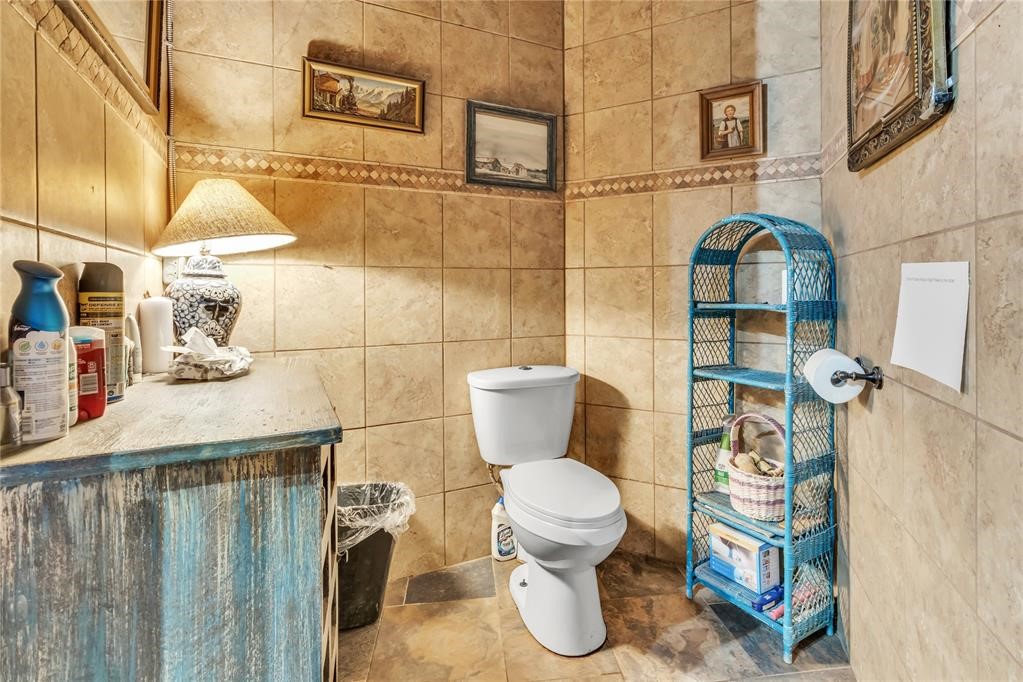 7676 W County Road 66, Mulhall, OK 73063 bathroom featuring vanity, toilet, tile floors, and tile walls