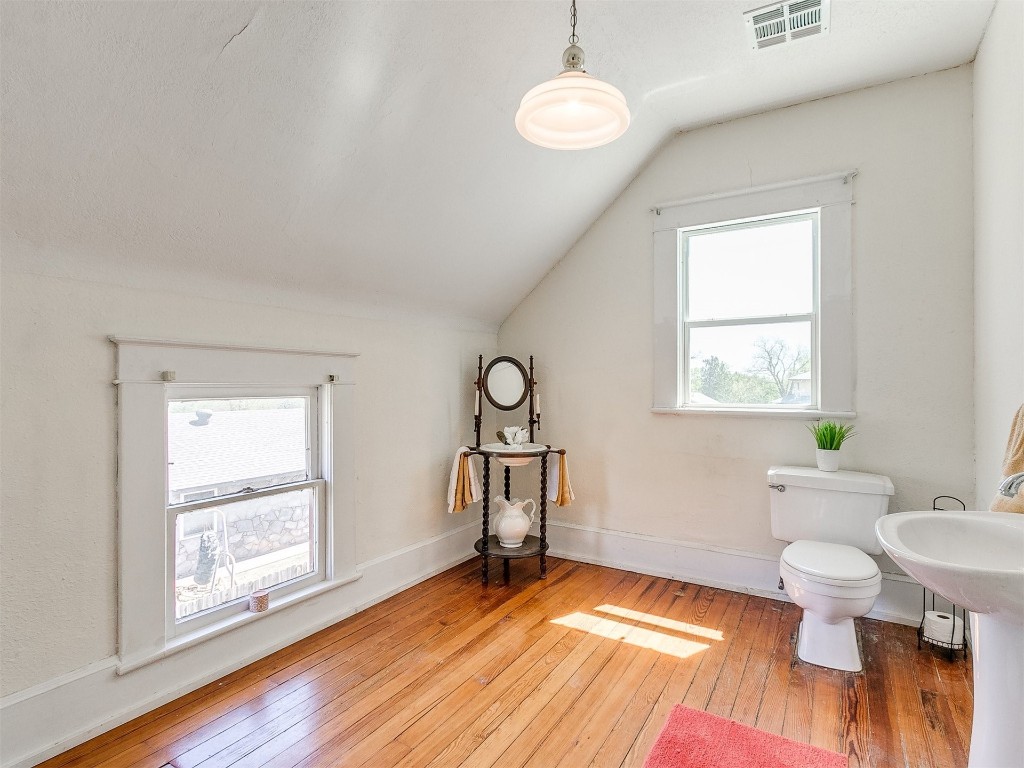 1623 W Oklahoma Avenue, Guthrie, OK 73044 bathroom with lofted ceiling, hardwood / wood-style flooring, and toilet