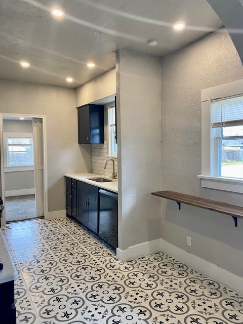 910 W Wade Street, El Reno, OK 73036 kitchen featuring light tile floors, sink, dishwasher, tasteful backsplash, and blue cabinetry