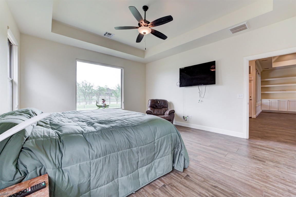 12712 Bristlecone Pine Boulevard, Oklahoma City, OK 73142 bedroom featuring hardwood / wood-style floors, ceiling fan, and a raised ceiling