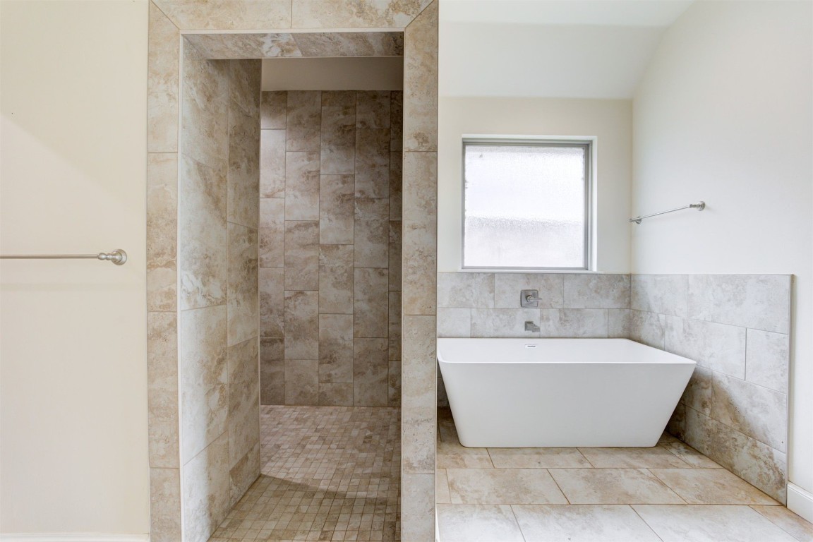 12712 Bristlecone Pine Boulevard, Oklahoma City, OK 73142 bathroom with tile flooring, a bathing tub, and tile walls
