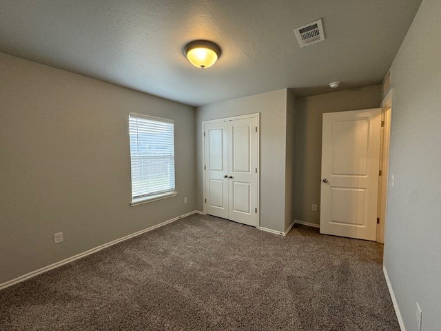 405 Vista Drive, Yukon, OK 73099 unfurnished bedroom with a closet and dark colored carpet
