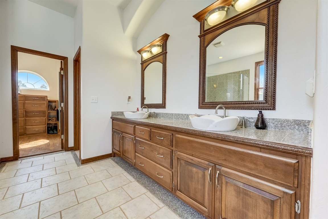 5608 E 68th Street, Stillwater, OK 74074 bathroom featuring dual sinks, an enclosed shower, tile floors, and vanity with extensive cabinet space