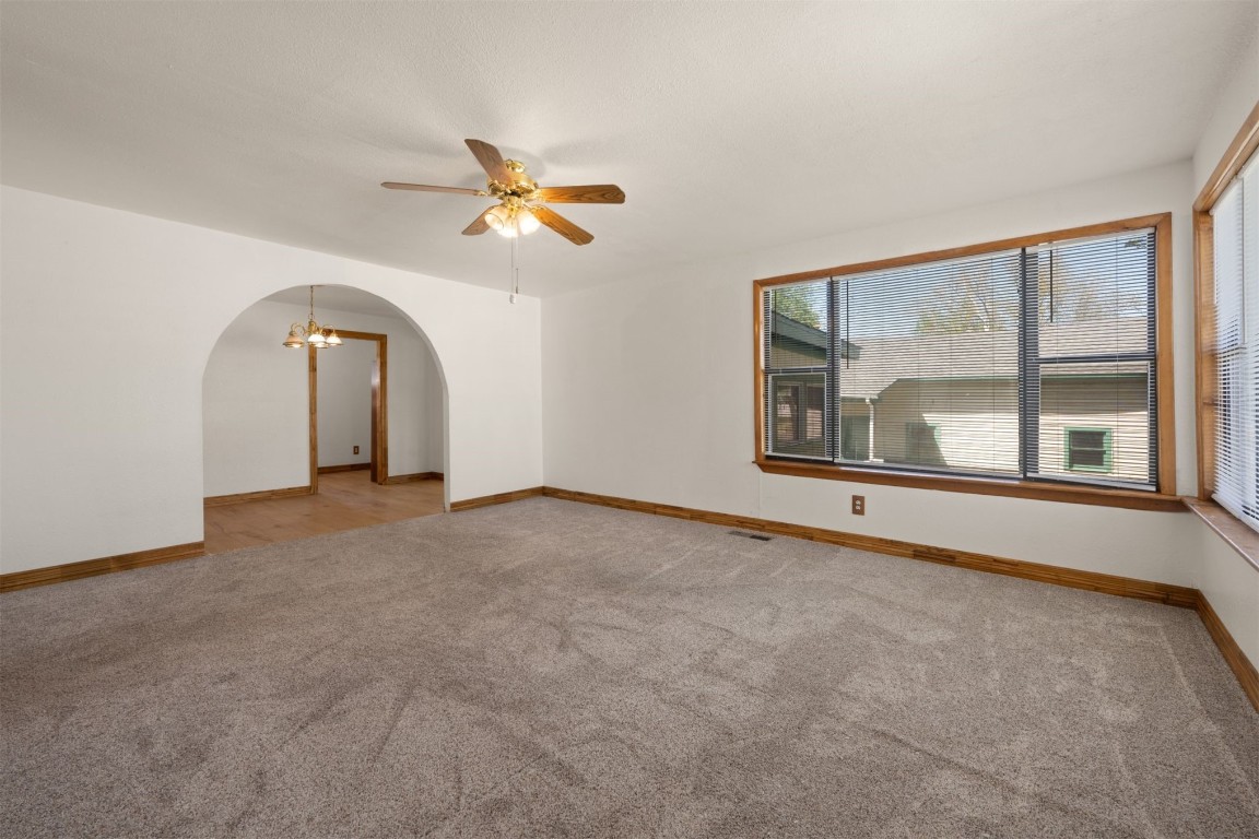 1902 W Noble Avenue, Guthrie, OK 73044 carpeted empty room featuring ceiling fan with notable chandelier