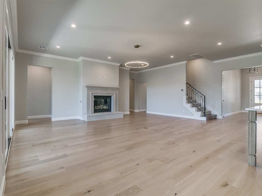 2201 Pallante Street, Edmond, OK 73034 unfurnished living room featuring crown molding and light hardwood / wood-style floors