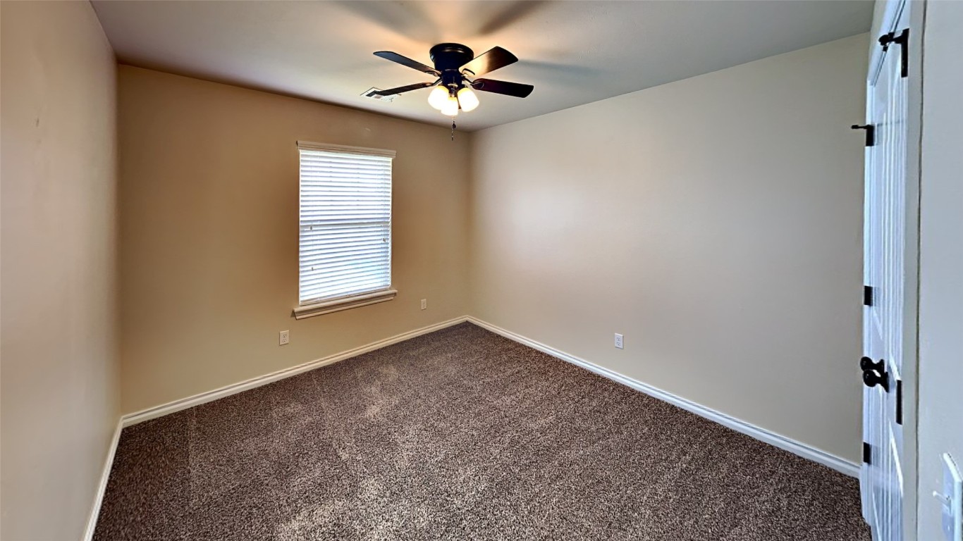 18220 Camborne Avenue, Edmond, OK 73012 empty room featuring dark colored carpet and ceiling fan