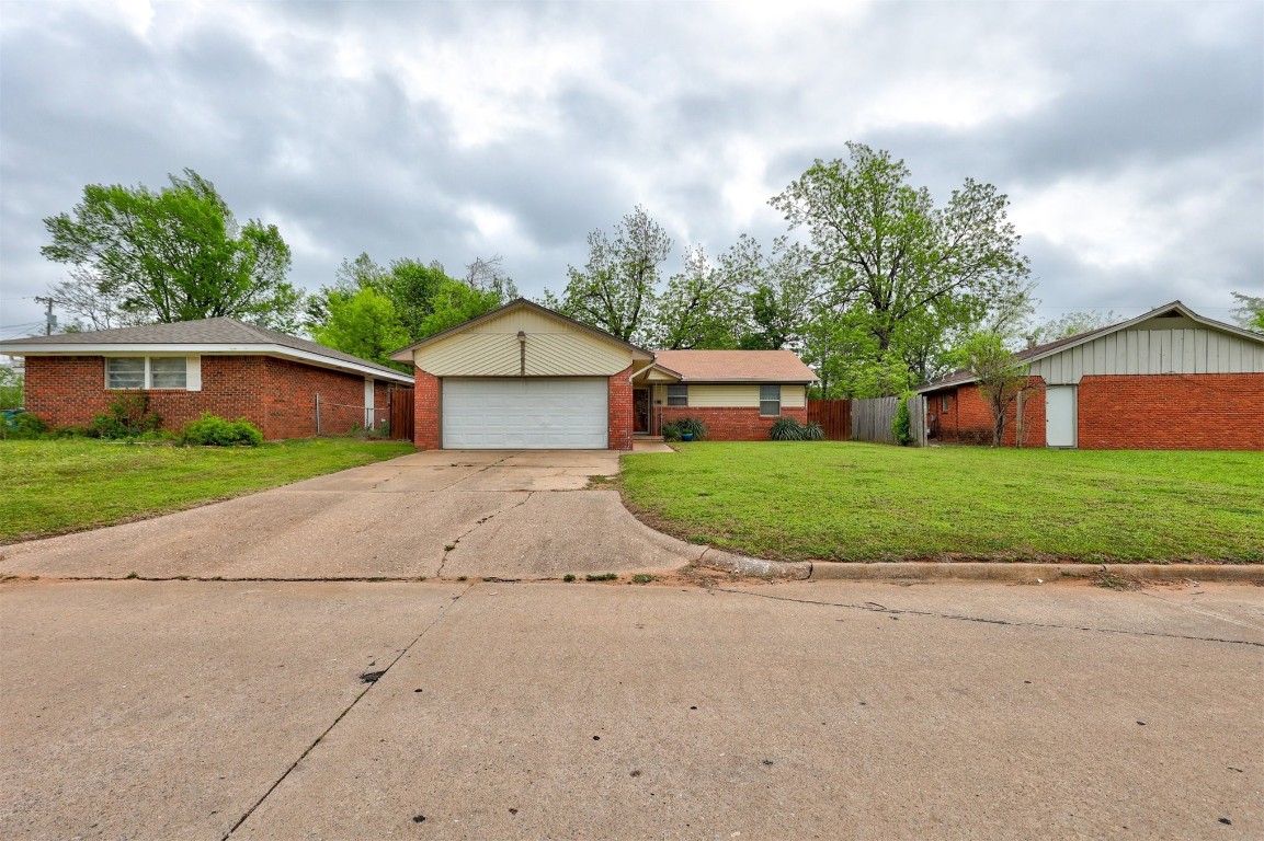 704 Juniper Avenue, Midwest City, OK 73130 ranch-style house with a garage and a front yard