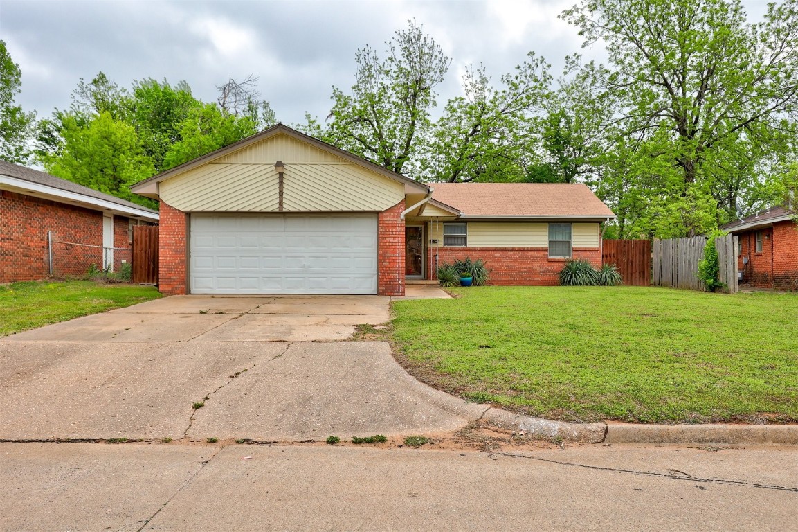 704 Juniper Avenue, Midwest City, OK 73130 ranch-style house featuring a front yard and a garage