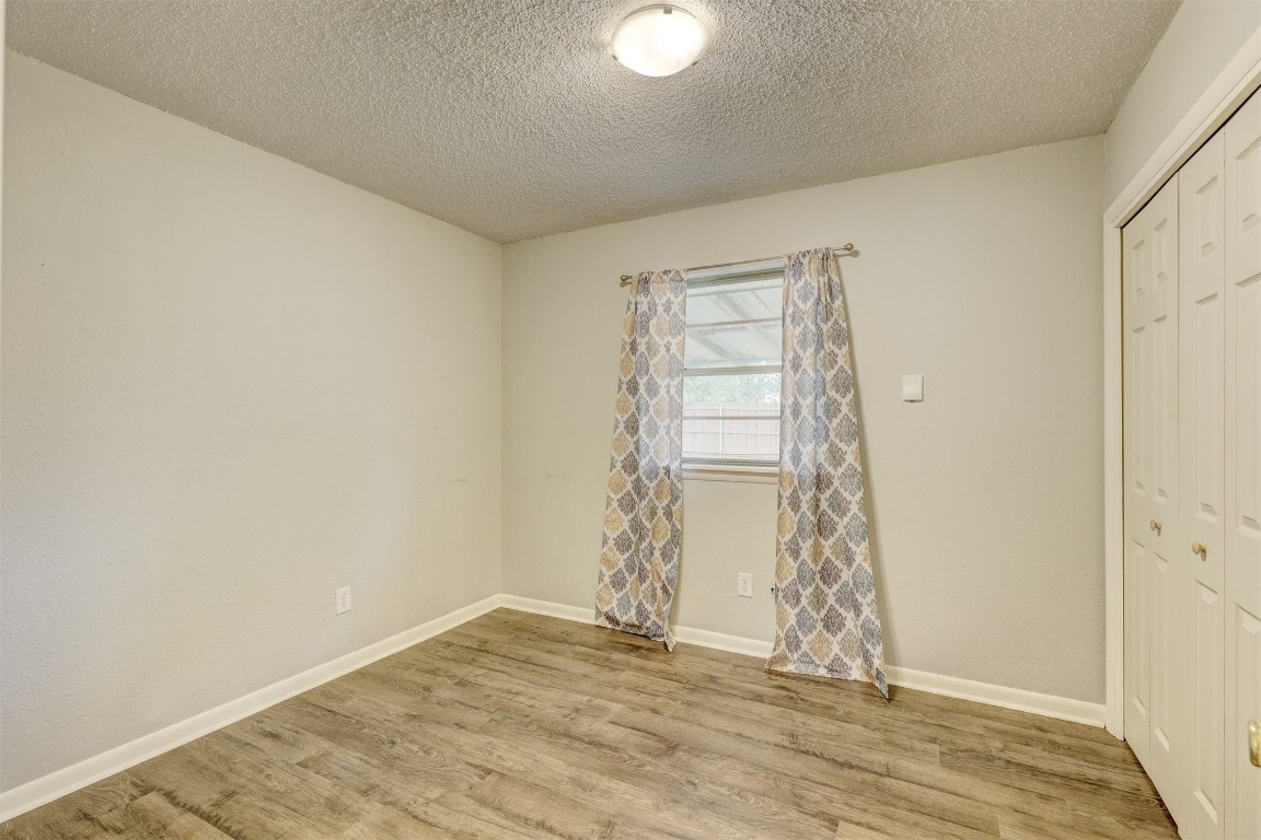 704 Juniper Avenue, Midwest City, OK 73130 unfurnished bedroom featuring a closet, light hardwood / wood-style flooring, and a textured ceiling
