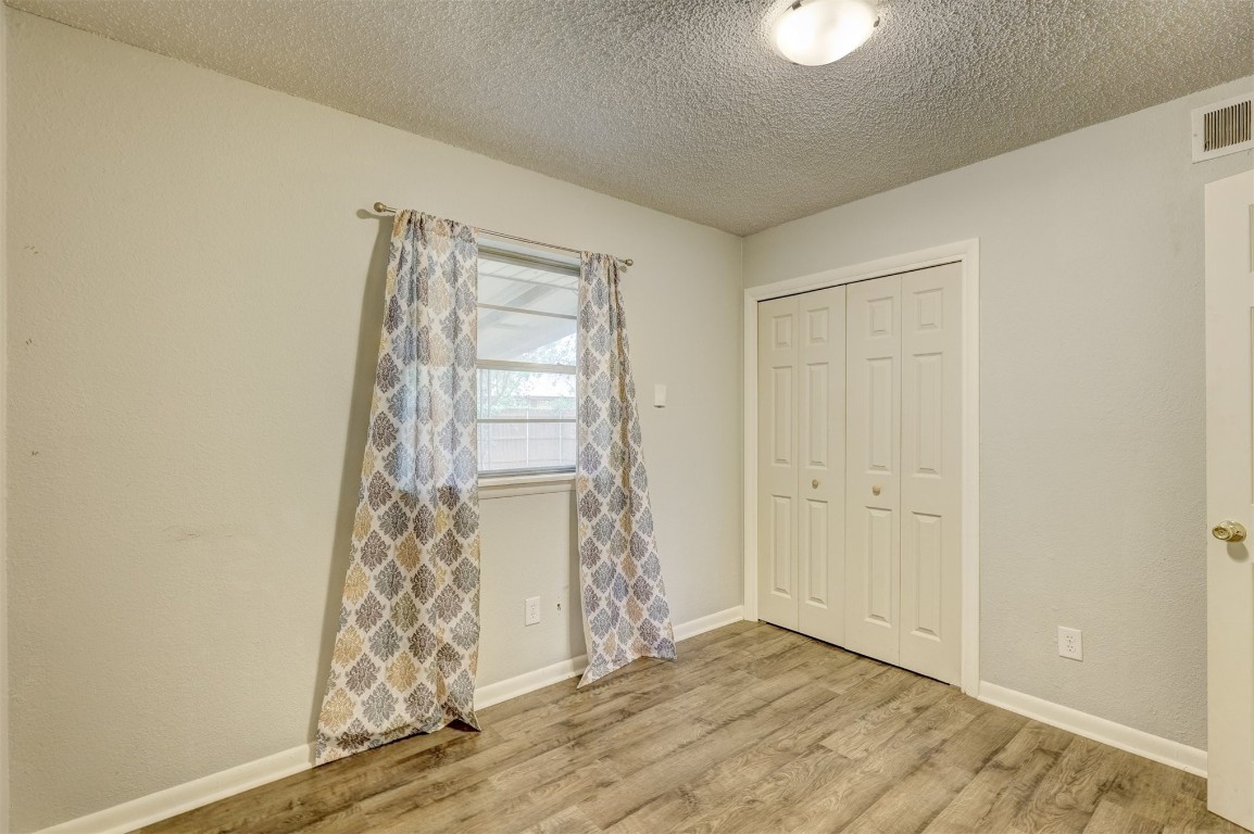 704 Juniper Avenue, Midwest City, OK 73130 unfurnished bedroom with a closet, a textured ceiling, and light hardwood / wood-style floors