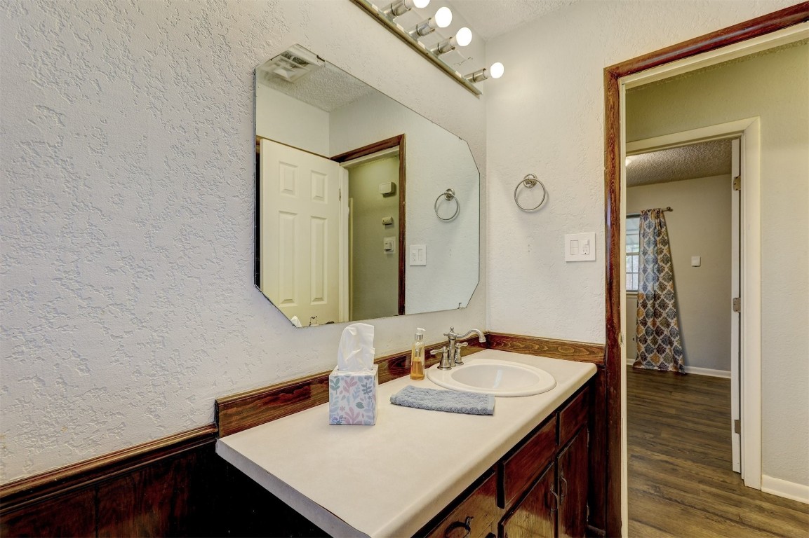 704 Juniper Avenue, Midwest City, OK 73130 bathroom featuring a textured ceiling, vanity, and hardwood / wood-style flooring