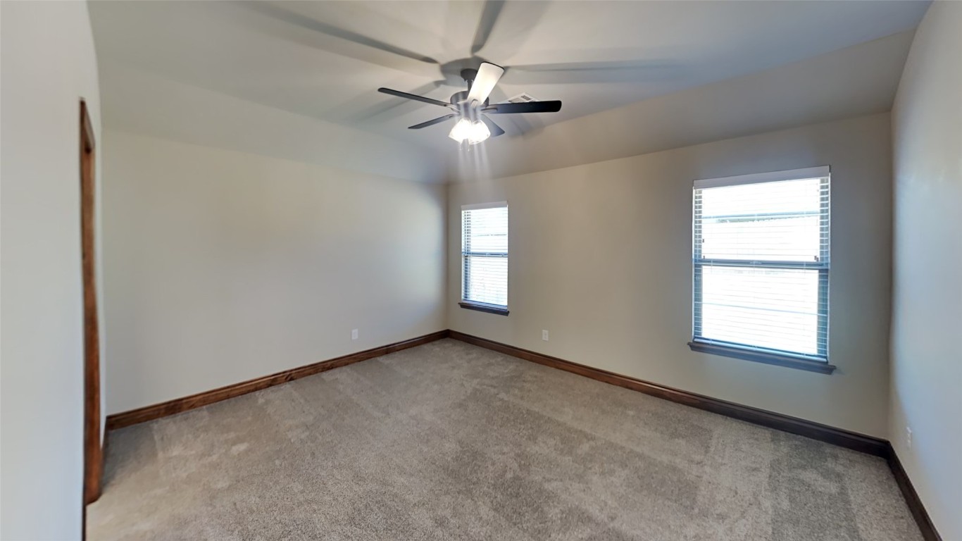 9013 NW 143rd Street, Yukon, OK 73099 empty room with light colored carpet, a wealth of natural light, and ceiling fan